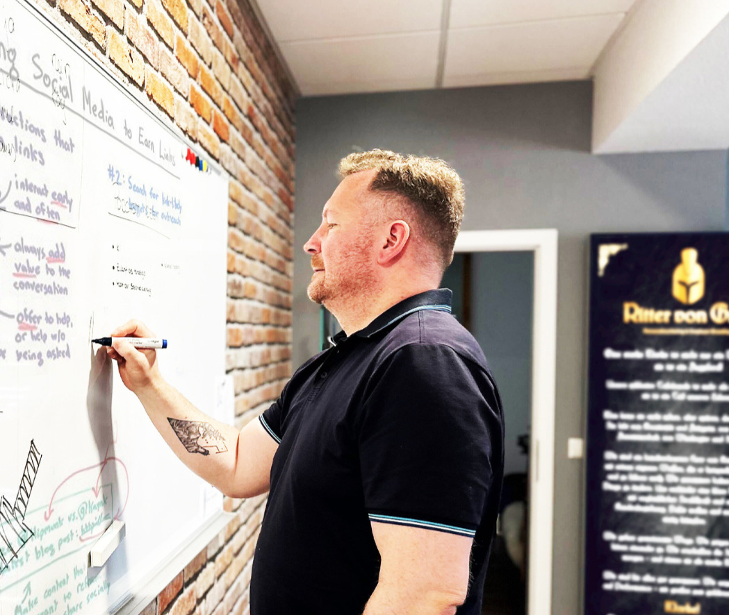 Mitarbeiter steht an der Tafel und stellt sein Konzept vor.